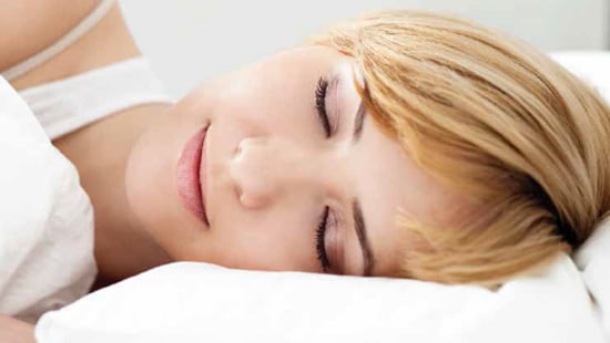 A woman sleeping on clean, soft, and white sheets.