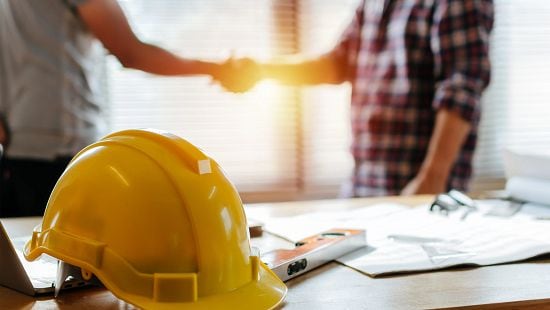 Two people shaking hands at construction planning site